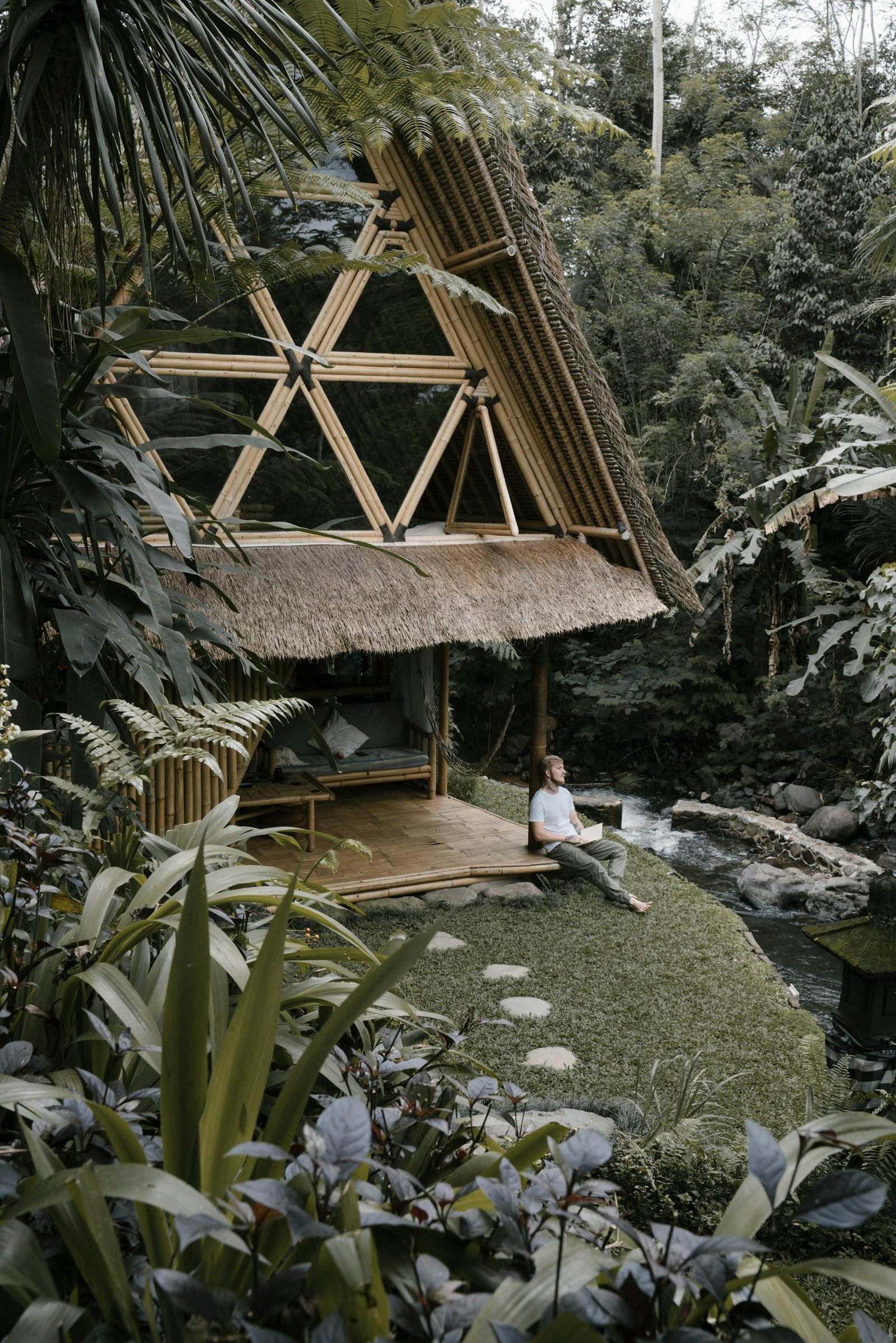 Peaceful bamboo hut in lush jungle by a serene river, perfect for relaxation.