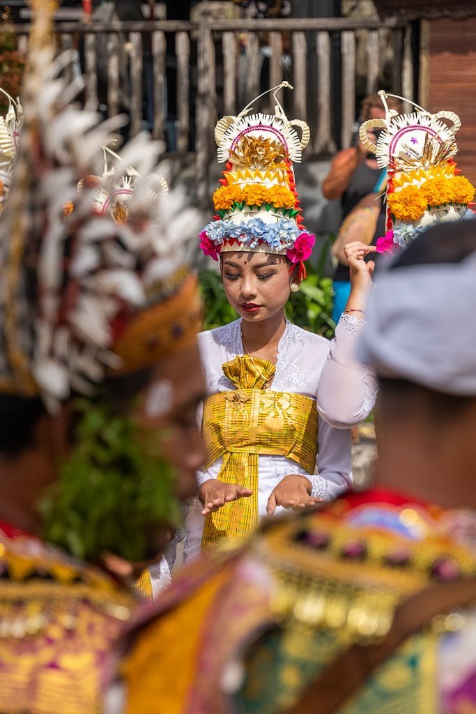 A colorful traditional Balinese ceremony featuring participants in intricate costumes and floral headdresses.