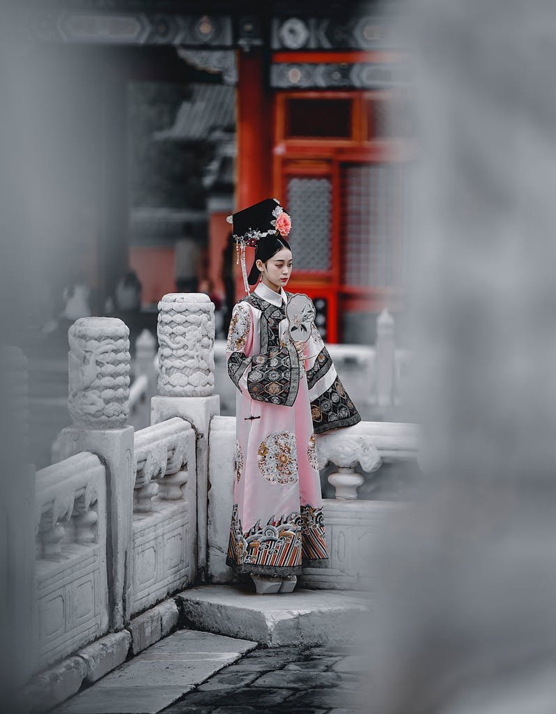 A woman in traditional Chinese clothing stands gracefully at the Forbidden City, showcasing cultural heritage and historical beauty.