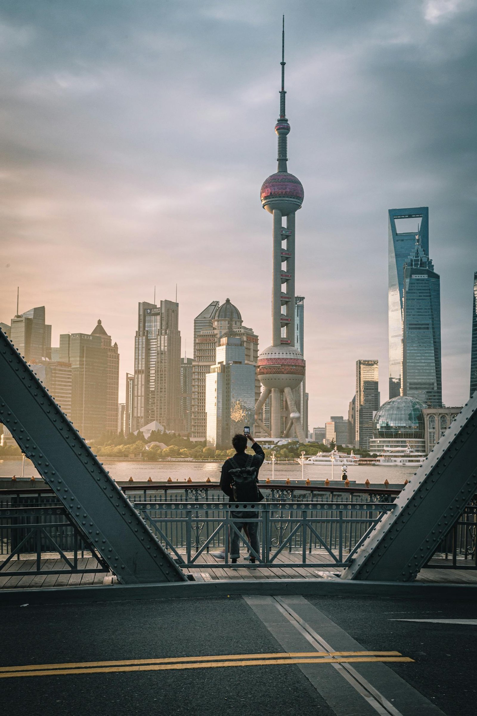 Captivating view of Shanghai's skyline and Oriental Pearl Tower at sunrise, featuring a person taking photos.