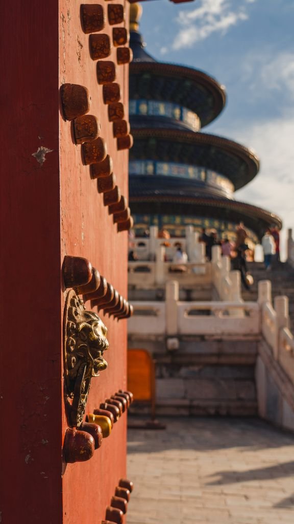 Detailed view of a traditional gate with the Temple of Heaven in Beijing, China in the background.