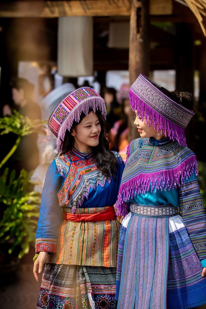 Two women wearing colorful traditional clothing at an outdoor cultural festival.